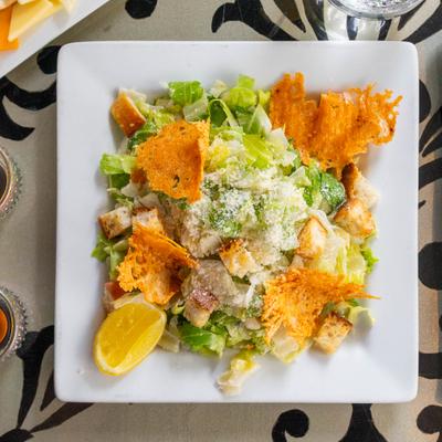 Caesar salad with Parmesan crisps, croutons and grated cheese on a plate.
