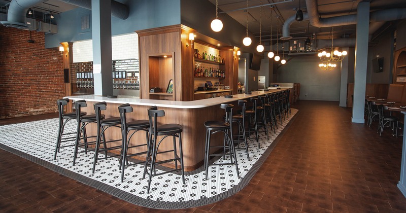 A modern bar interior with a white countertop and black stools