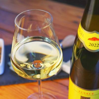 A glass of white wine next to a bottle.