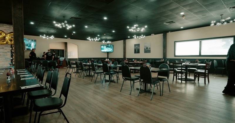 An interior view of a modern restaurant dining area, dark ceiling, and arranged tables and chairs