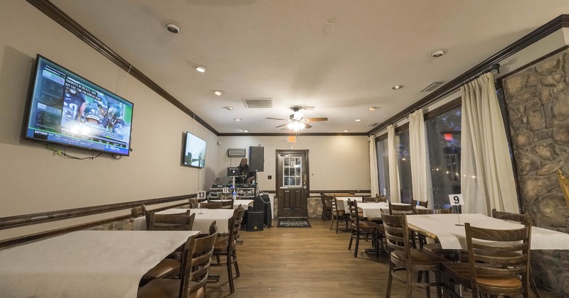 Interior, dining tables, TVs on a wall, DJ stage in the back of the room