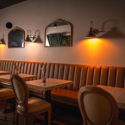 Cozy dining area with banquette seating, chairs, mirrors and warm lighting.