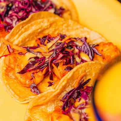 Shrimp tacos topped with cabbage and orange sauce.