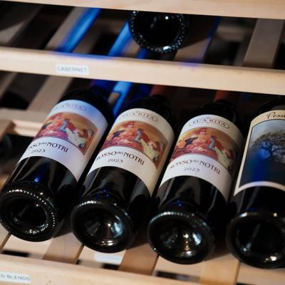 Red wine bottles on a wooden rack.