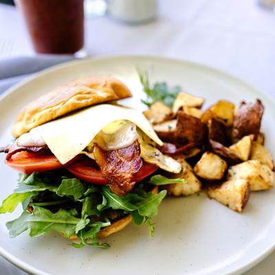 Bacon cheeseburger with arugula, tomato, and roasted potatoes.