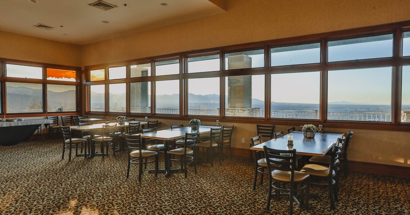 Dining area, large windows, black tables and chairs, decorative flower arrangements
