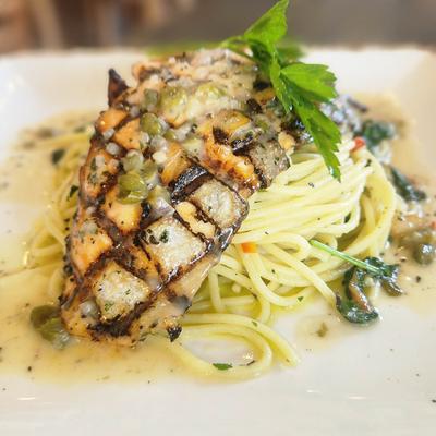 A grilled chicken piccata served with pasta.