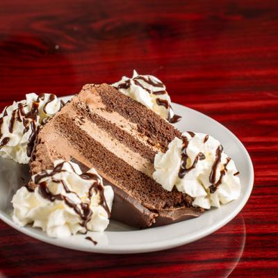 Chocolate Mousse Cake served with whipped cream and chocolate drizzle.