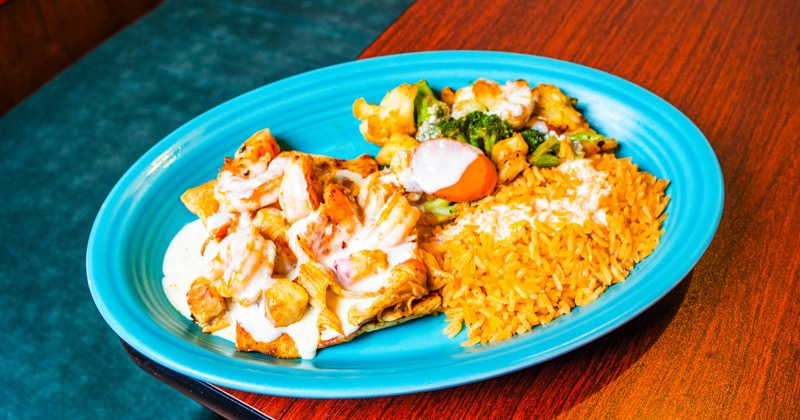 Grilled chicken and shrimp topped with white sauce, with veggies and rice