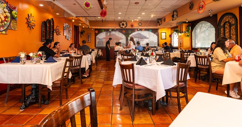 Restaurant interior, dining area with set tables, guests enjoying their food and drinks