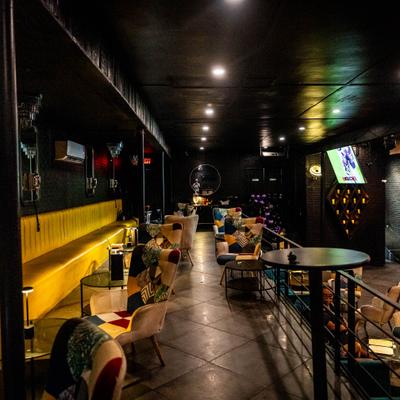 Interior with a long yellow bench seating and small tables down the center aisle.