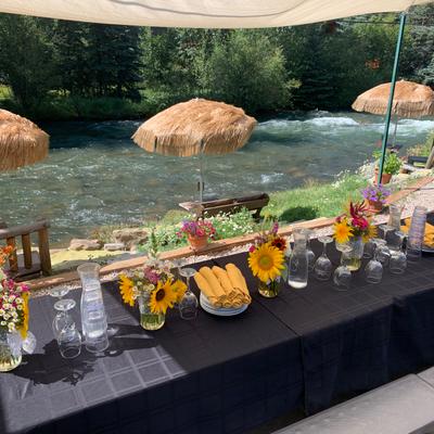 A long table set for dining outside with a view of the river.