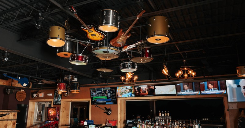 Bar interior with a guitar and drum set chandelier and TVs