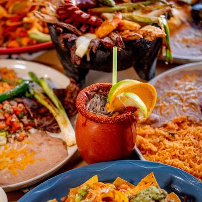 Assorted food dishes on a table with a cantarito mug in the center.