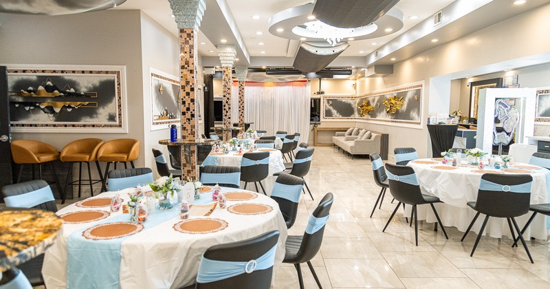 A luxurious banquet hall with set round dining tables and stylish black chairs