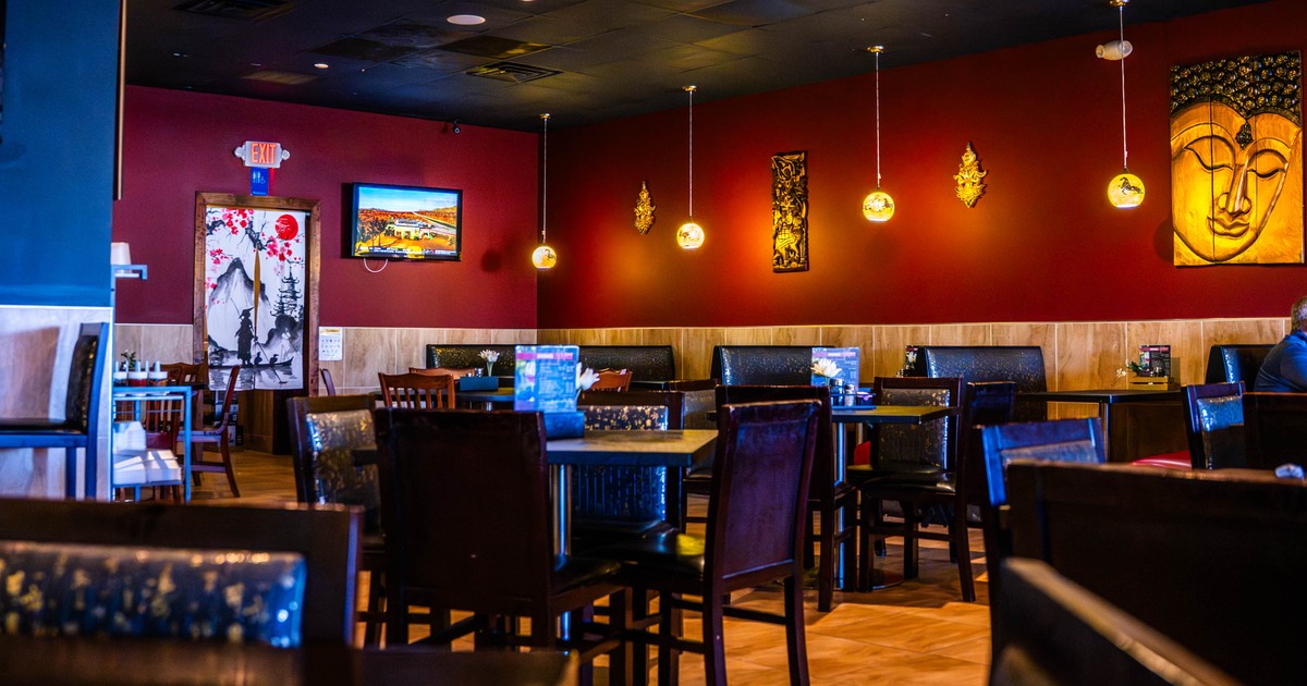 Interior of a warmly decorated restaurant with red walls, pendant lights, and dark wooden seating