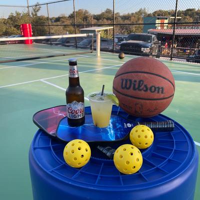 Pickleball paddles, balls, a basketball, beer, and a cocktail.