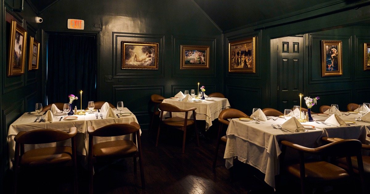 Elegant restaurant room featuring candlelit tables, artwork, and upholstered seating