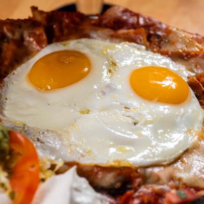 Sunny side eggs over chilaquiles on plate, extreme close up.