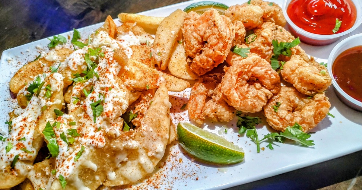 Shrimp cocktail, loaded fries, and a cocktail drink