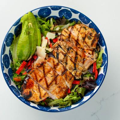 Grilled chicken salad with greens, avocado, and tortilla strips.