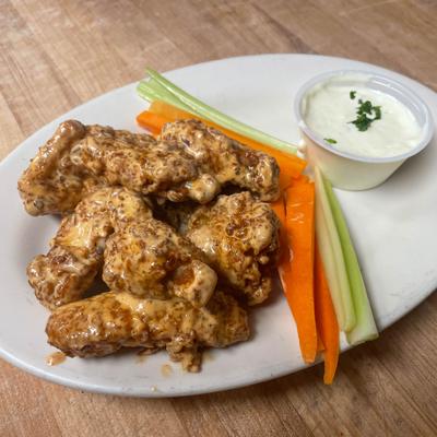 Chicken wings with creamy sauce served with celery, carrots, and dipping sauce.