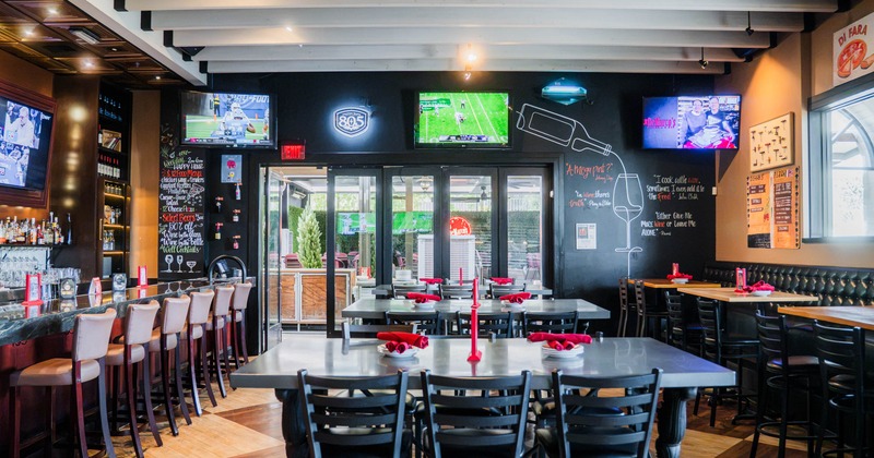 Interior of a restaurant with a bar, sports televisions and dining tables