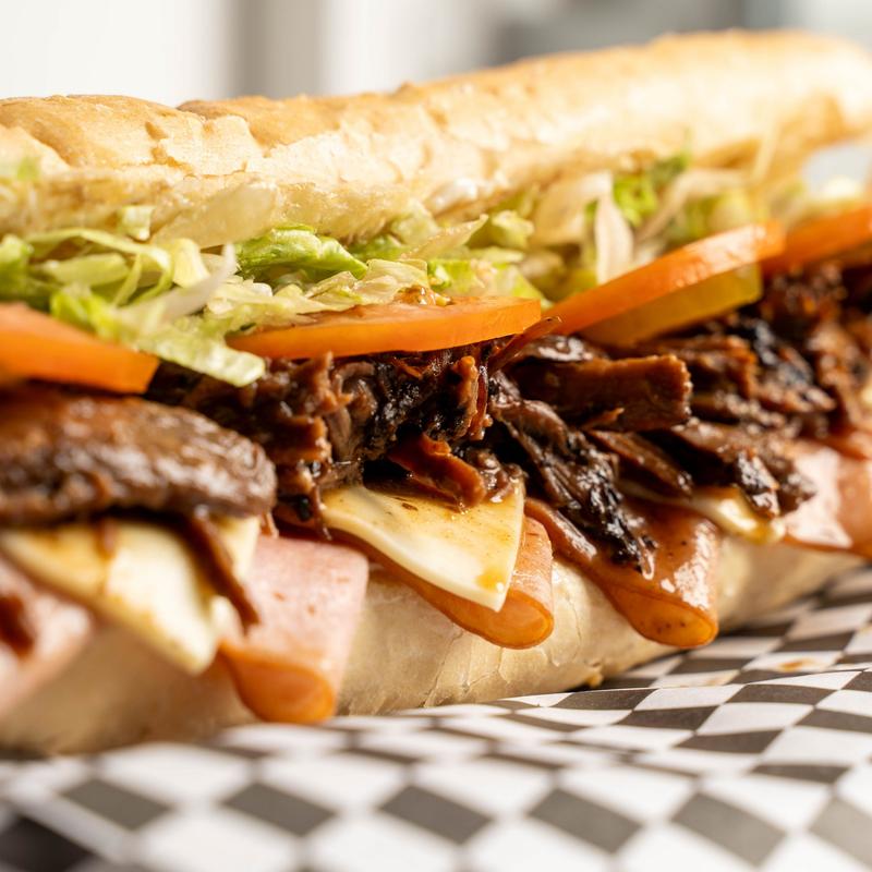 Roast beef sandwich, with ham, Swiss cheese, mayo, lettuce, tomatoes, and pickles.