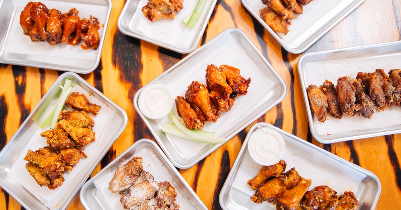 Chicken wings assortment with dry rub wings, sauced wings, ranch dipping sauce, and celery on metal trays