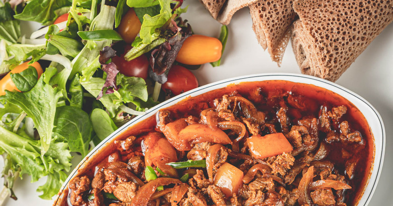 Small cuts of lamb with onion, pepper, tomatoes in sauce, served with salad and bread