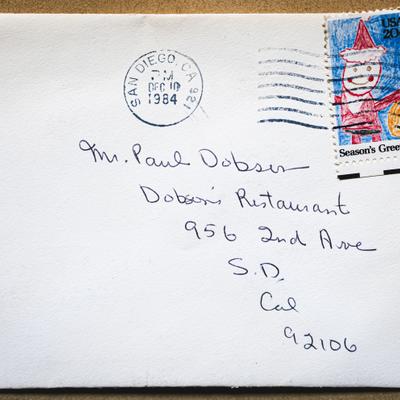 An envelope with a handwritten name and address and a Season's Greetings stamp