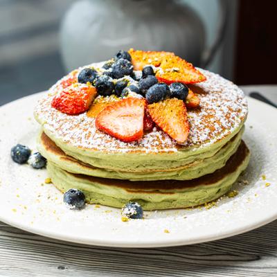 Stack of pancakes toppped with berries and dusted with powdered sugar.