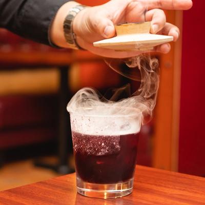 Cocktail in rocks glass being smoked on the table.