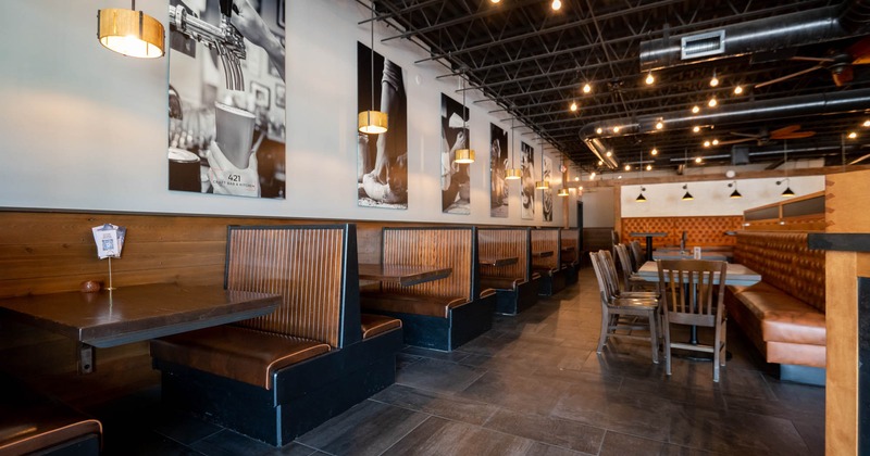 A modern restaurant interior with wooden booths, black-and-white photographs, and pendant lights