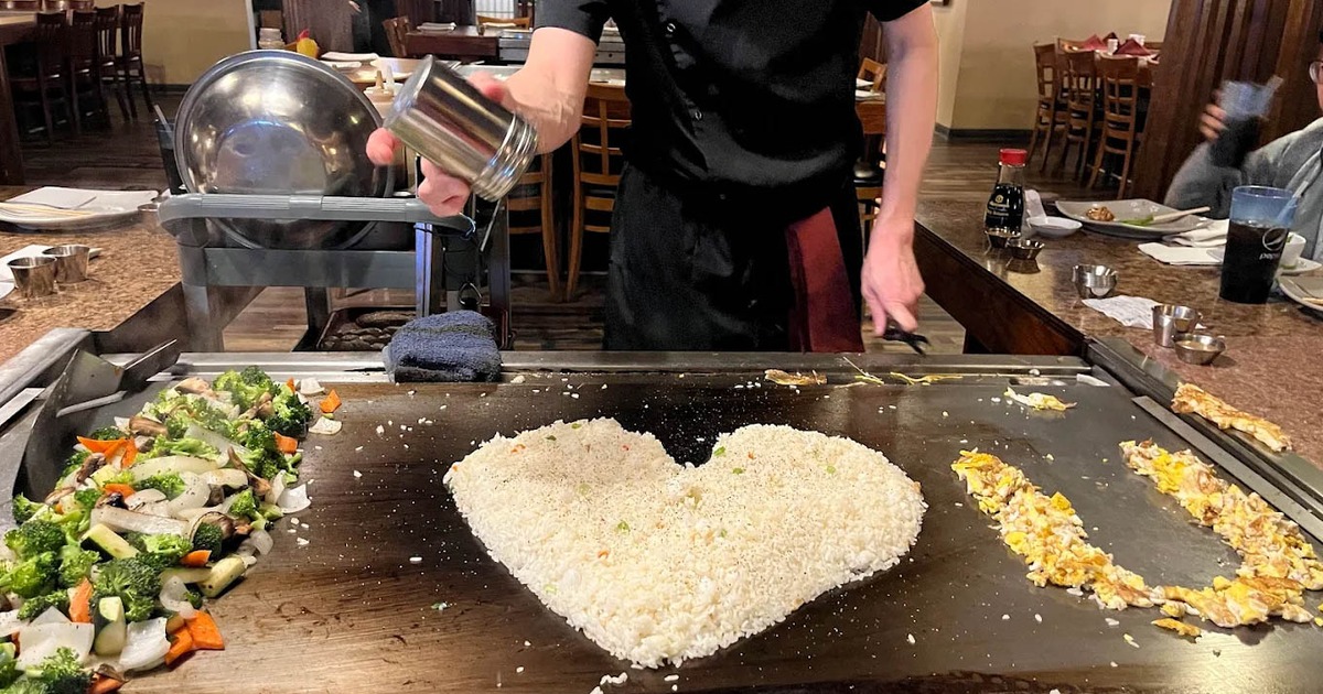 Teppanyaki chef creating a heart-shaped mound of fried rice on a hot grill