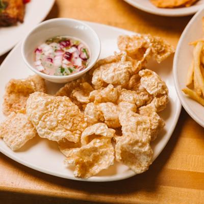 Crispy pork rinds served with a dipping sauce.