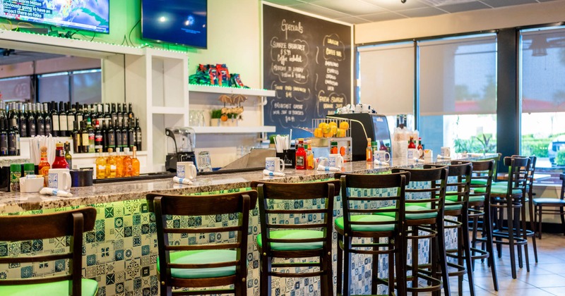 Interior, bar with bar stools, small format tile decoration, wine shelf in the back