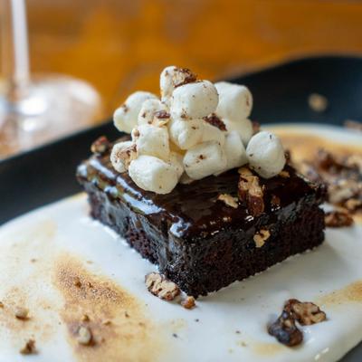 Chocolate brownie topped with marshmallows and nuts.