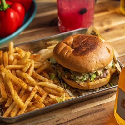 Mexican Burger served on a metal tray line with paper with a side of fries.