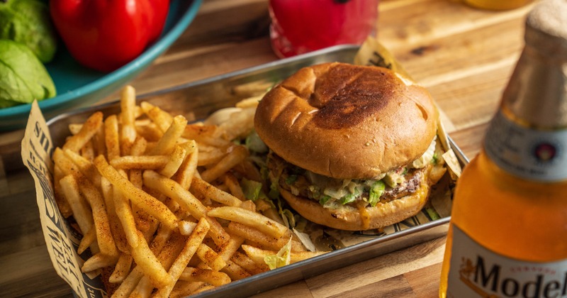 Mexican Burger with a side of fries, served alongside a cocktail