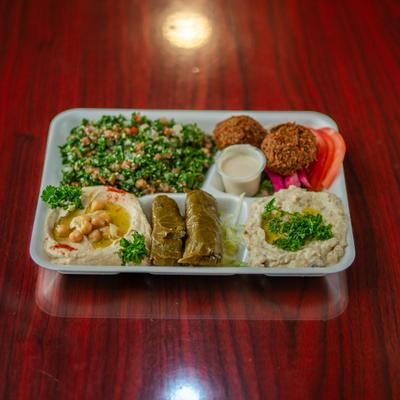 Lebanese mezze plate with hummus, baba ganoush, tabbouleh, falafel, grape leaves, and tahini.