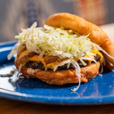 Cheeseburger topped with lettuce on a frybread bun.