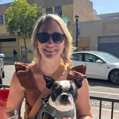 woman smiling holding a black and white dog.