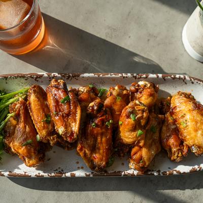 A long platter of glazed chicken wings garnished with fresh green onions.