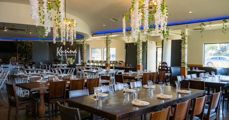 Interior with decorated ceiling lights, wooden tables set with glasses and napkins