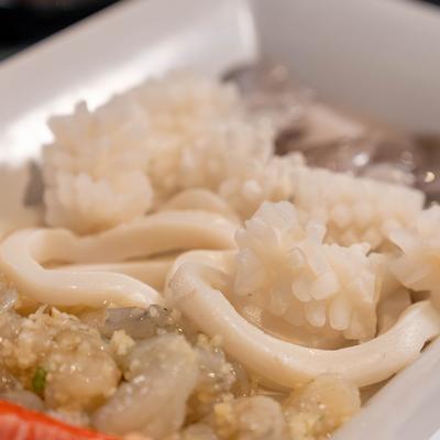 Platter of raw seafood, including squid, shrimp, and octopus, close-up.