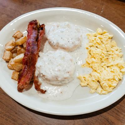 Biscuits and gravy with crispy bacon, scrambled eggs, and home fries.