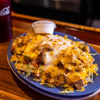 Ultimate Nacho Fiesta with meat, cheese, lettuce, tomatoes, onions, and jalapeños.