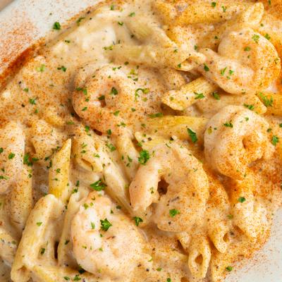 Close-up view of a creamy jumbo shrimp pasta topped with paprika and herbs.
