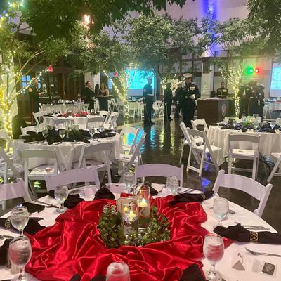 Military banquet event with red and black table decorations and uniformed officers standing nearby.